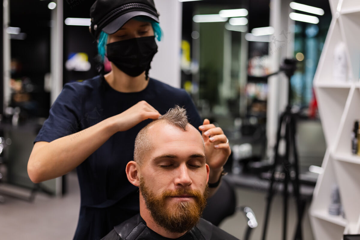 保护专业美发师戴着防护面罩 在美容院为欧洲胡须野蛮男子理发男人面具修剪