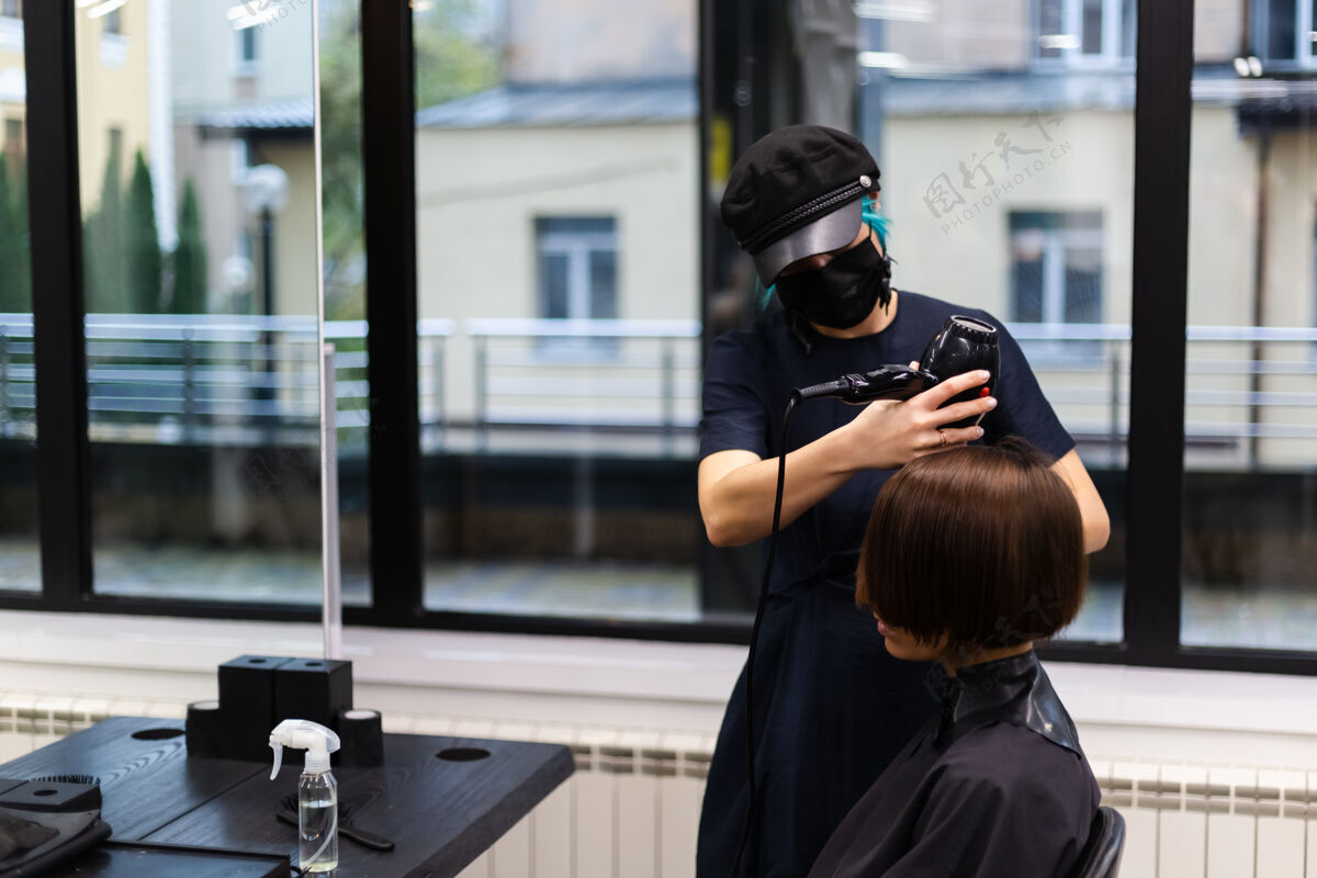 脸一个专业的女理发师给客户理发这个女孩戴着面具坐在美容院里面膜面部人
