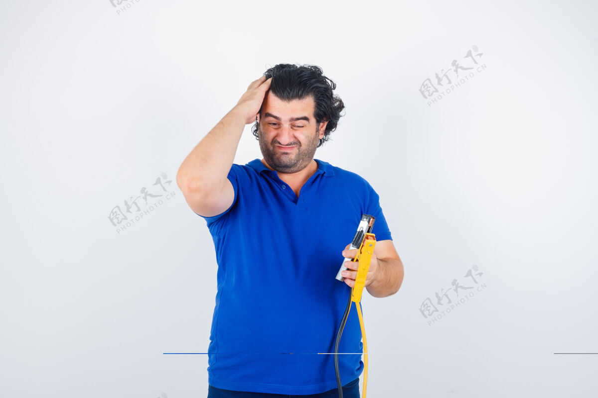 沉思身着蓝色t恤的成熟男子手持施工工具 用手梳理头发 神情若有所思 俯瞰前方肖像工具梳子