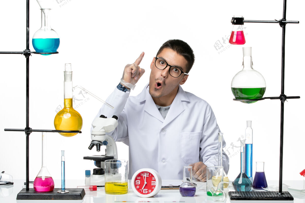 科学前视图穿着白色医疗服的男性化学家坐在白色背景病毒科学冠状病毒大流行实验室的解决方案上实验室专业人员医学