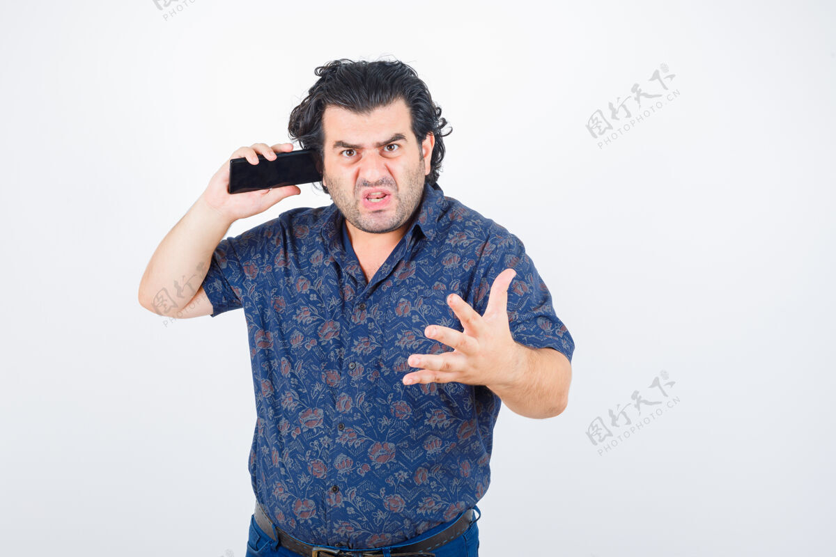 尖叫成熟的男人穿着衬衫在手机上聊天 看起来很愤怒 正面视图愤怒电话人