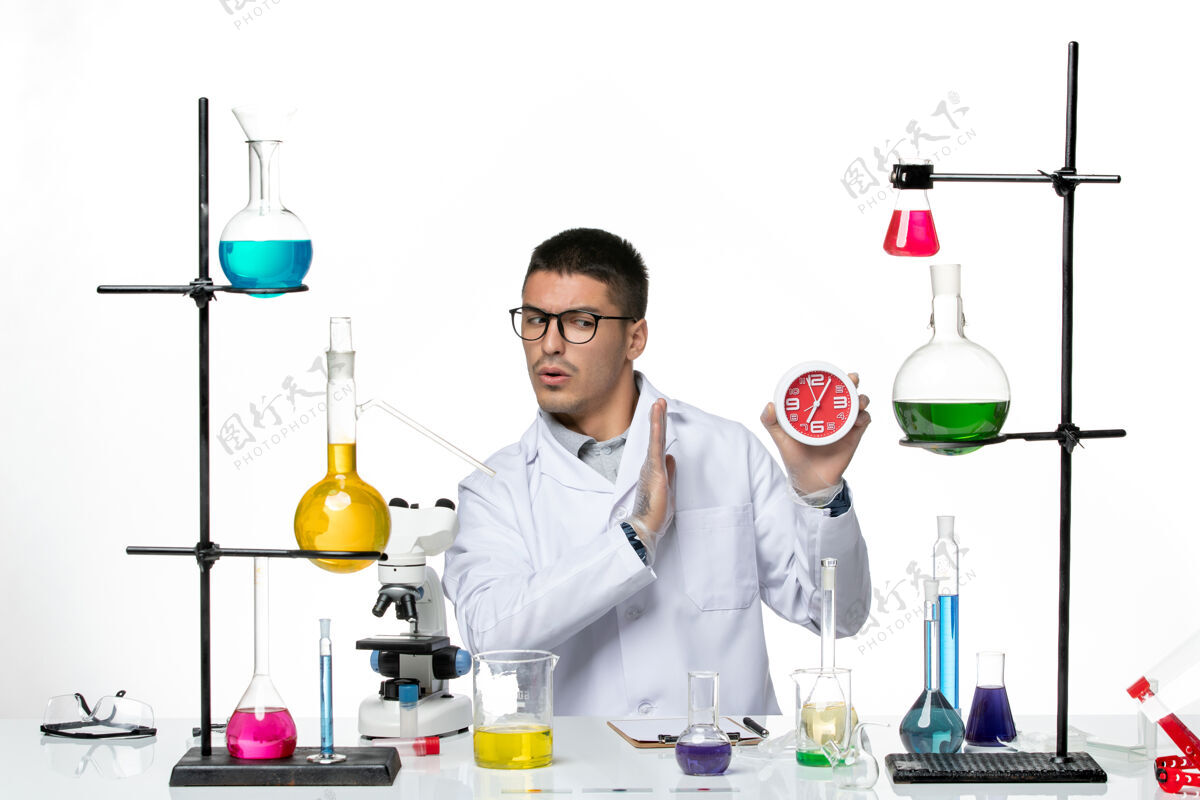 药正面图身穿白色医疗服的男性化学家拿着浅白色背景上的时钟 科维病毒疾病科学实验室持有人疾病