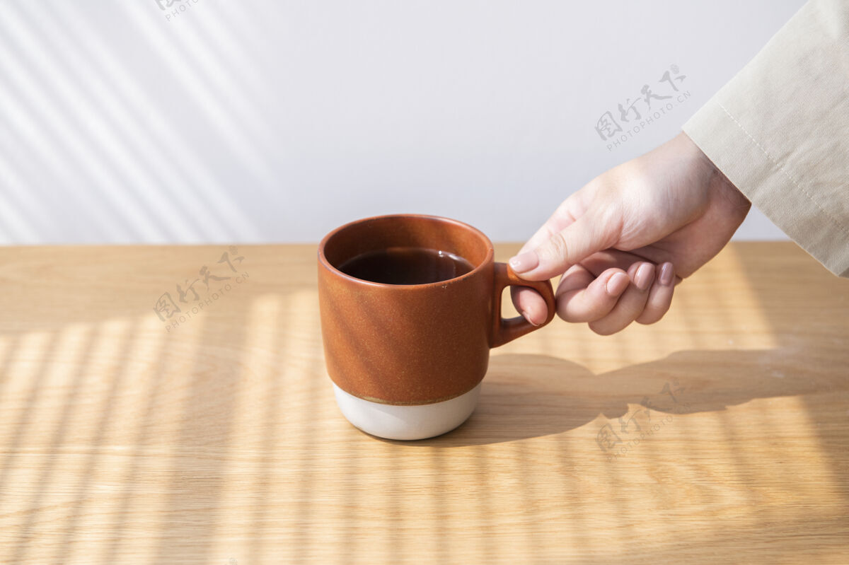 人从木桌上拿咖啡杯的女人咖啡休息最小的家具木制家具