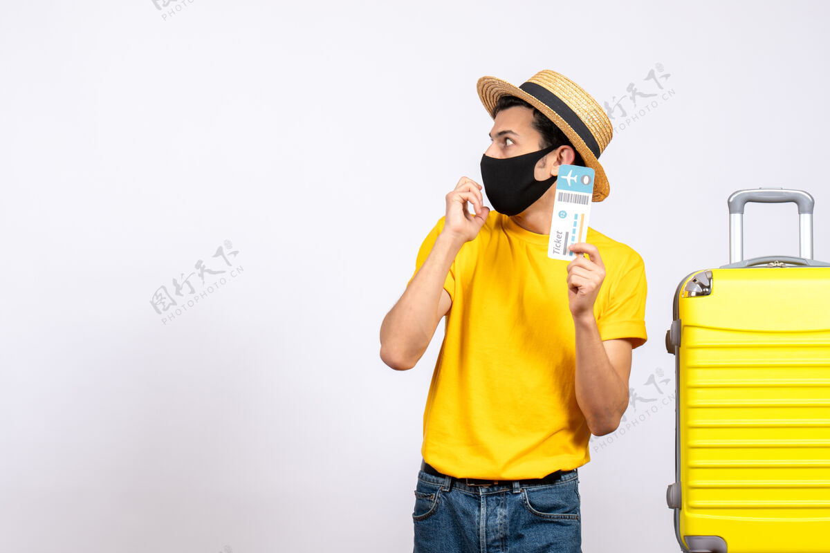 男性游客正面图戴草帽的男游客站在黄色手提箱旁 手里拿着机票专业人士持有稻草