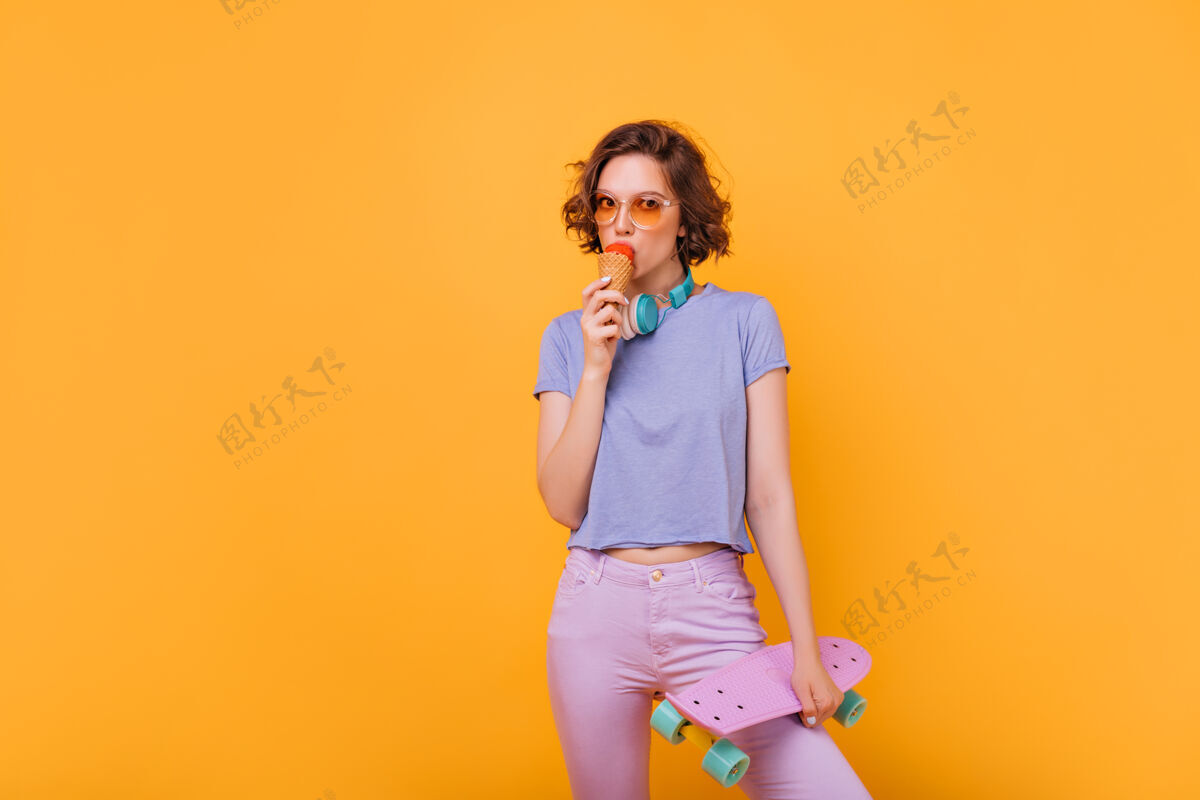 休闲漂亮的女孩 深色短发 吃着冰淇淋室内照片 一个穿着滑板的漂亮女人爱好放松酷