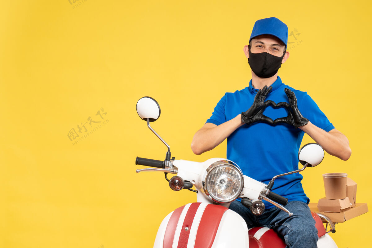 流行病正面图身着蓝色制服的男快递员在黄色快递上发送爱心病毒covid-服务工作自行车大流行工作病毒制服前面