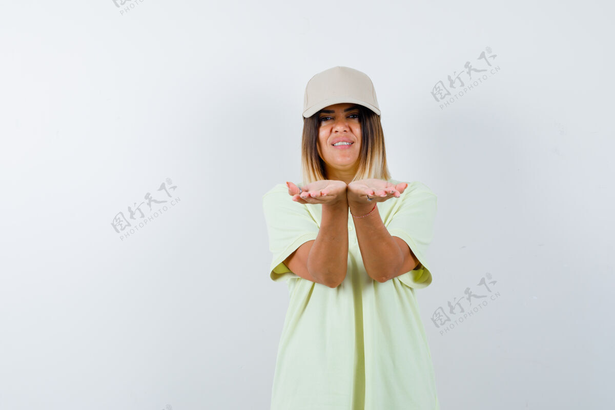 帽子年轻女性穿着t恤 戴着帽子 伸着杯形的手 看起来很可爱眼睛女性前面