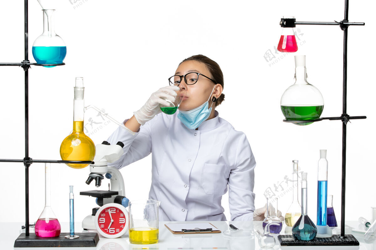 医学前视图穿着医疗服的女化学家 白色背景上戴着口罩饮用水飞溅实验室病毒化学冠状病毒实验室病毒溶液