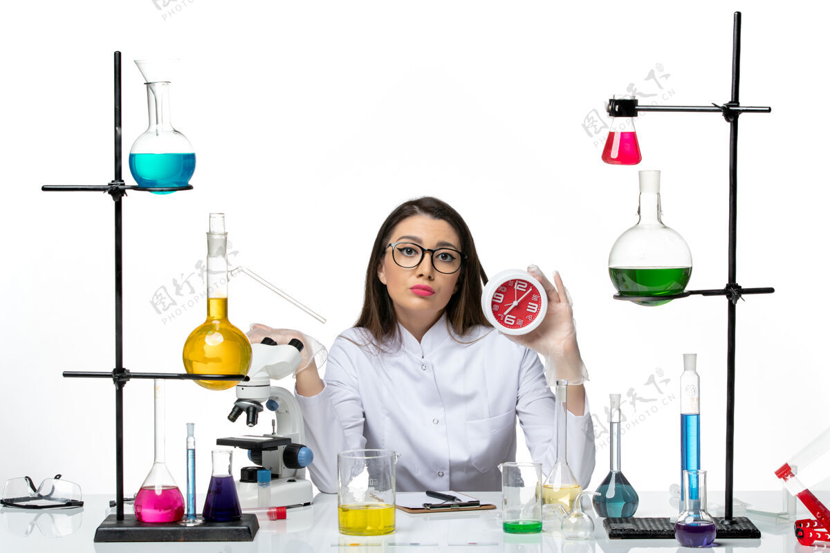 科学前视图穿着白色医疗服的女化学家拿着浅白色背景上的时钟科学病毒实验室病毒-大流行套装烧杯罐子