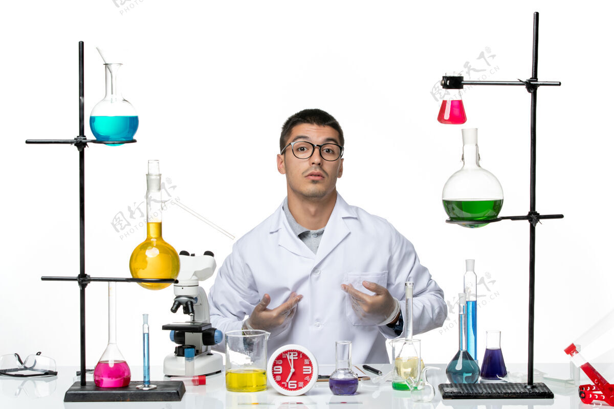 大流行正面图身着白色医疗服的男性化学家坐在白色背景病毒科学实验室的不同解决方案上实验室专业医院