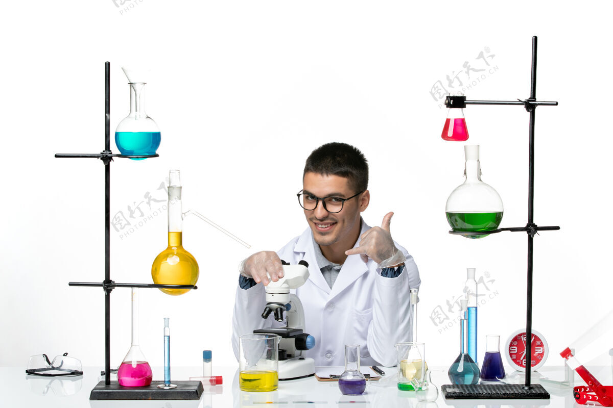 医学前视图男性化学家穿着白色医疗服 在白色背景上微笑着使用显微镜病毒冠状病毒-疾病实验室科学使用正面实验室