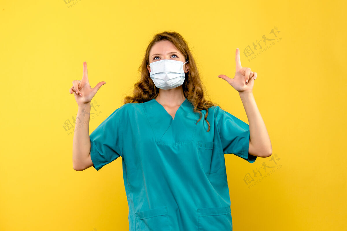 人黄色地板上戴着面罩的女医生的正面图医疗保健科维德大流行地板药生活方式