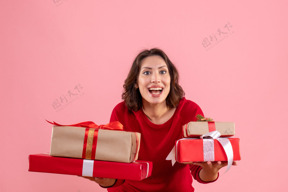 漂亮正面图年轻女性携带圣诞礼物的粉红色人风景微笑
