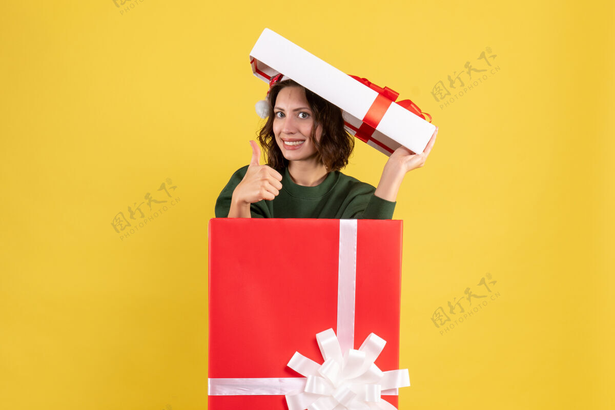 礼物前视图年轻女性躲在黄色盒子里节日快乐微笑