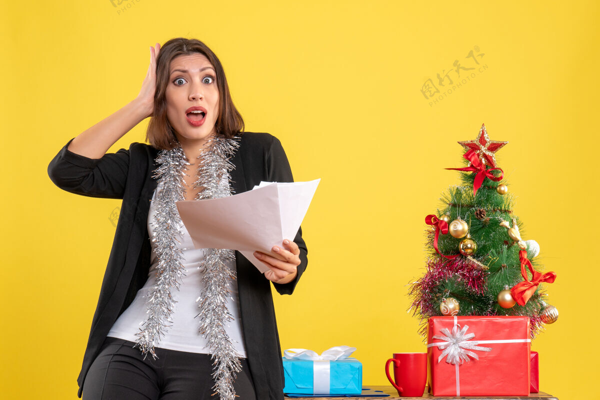 情绪圣诞节心情激动 惊喜美丽的女士站在办公室里 拿着黄色的文件在办公室里美丽文件人