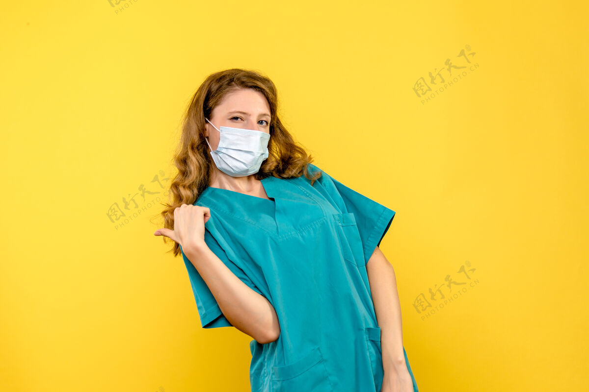 医学黄墙上戴着面具的女医生的正视图黄色女医生医学