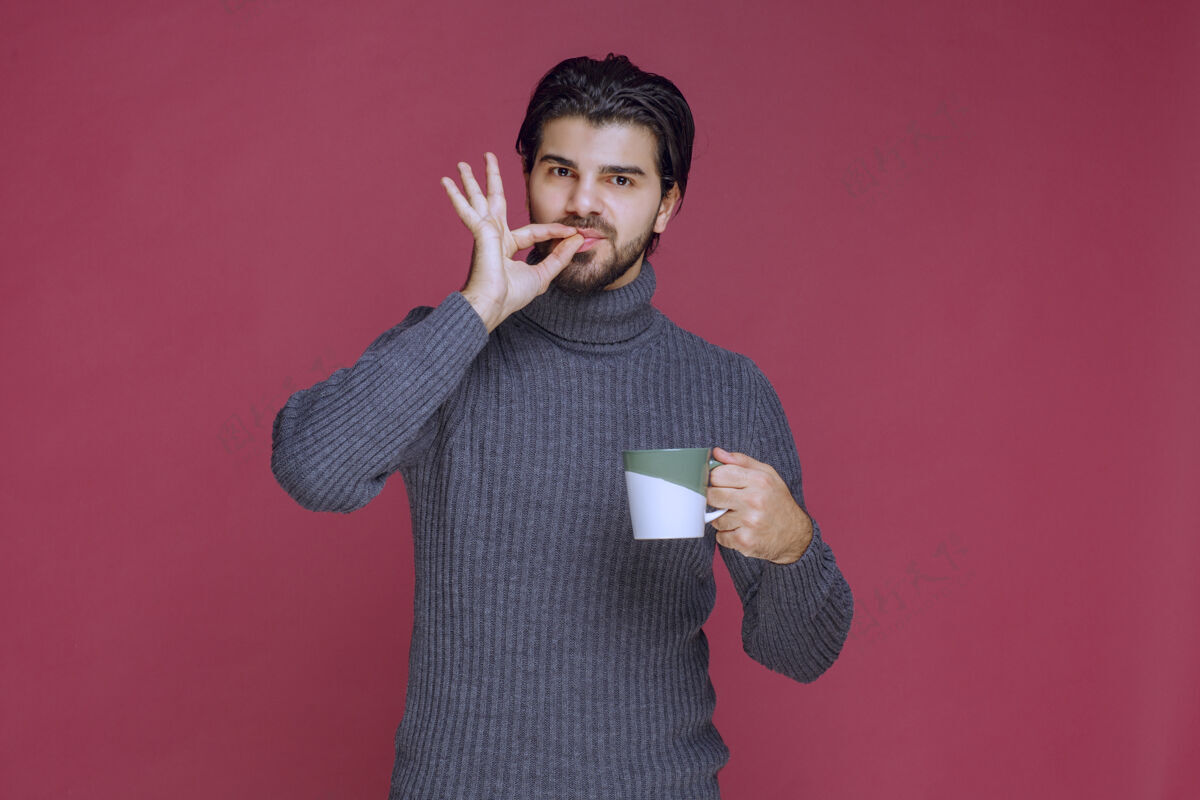 聪明穿着灰色毛衣的男人拿着咖啡杯 享受着咖啡的味道人休闲年轻