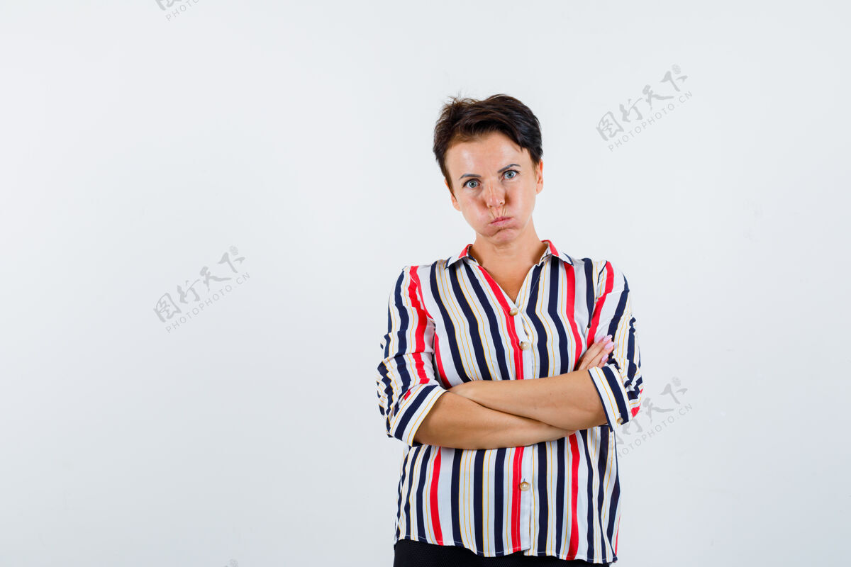 中成熟的女人交叉双臂站在条纹衬衫和期待无聊的前视图画像衬衫自然人