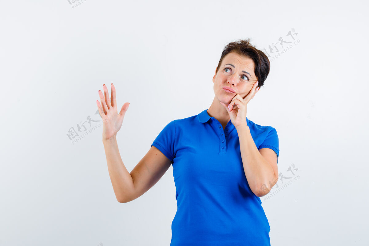 自然成熟的女人一边举手一边思考 穿着蓝色t恤 看上去很可疑 正面视图中间干净女性