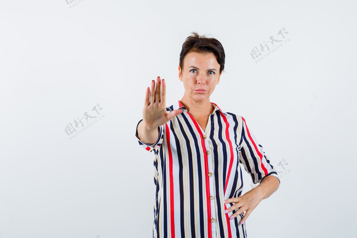 前面成熟的女人展示停车标志 手放在腰上 穿着条纹衬衫 表情严肃正面图信心年龄老年