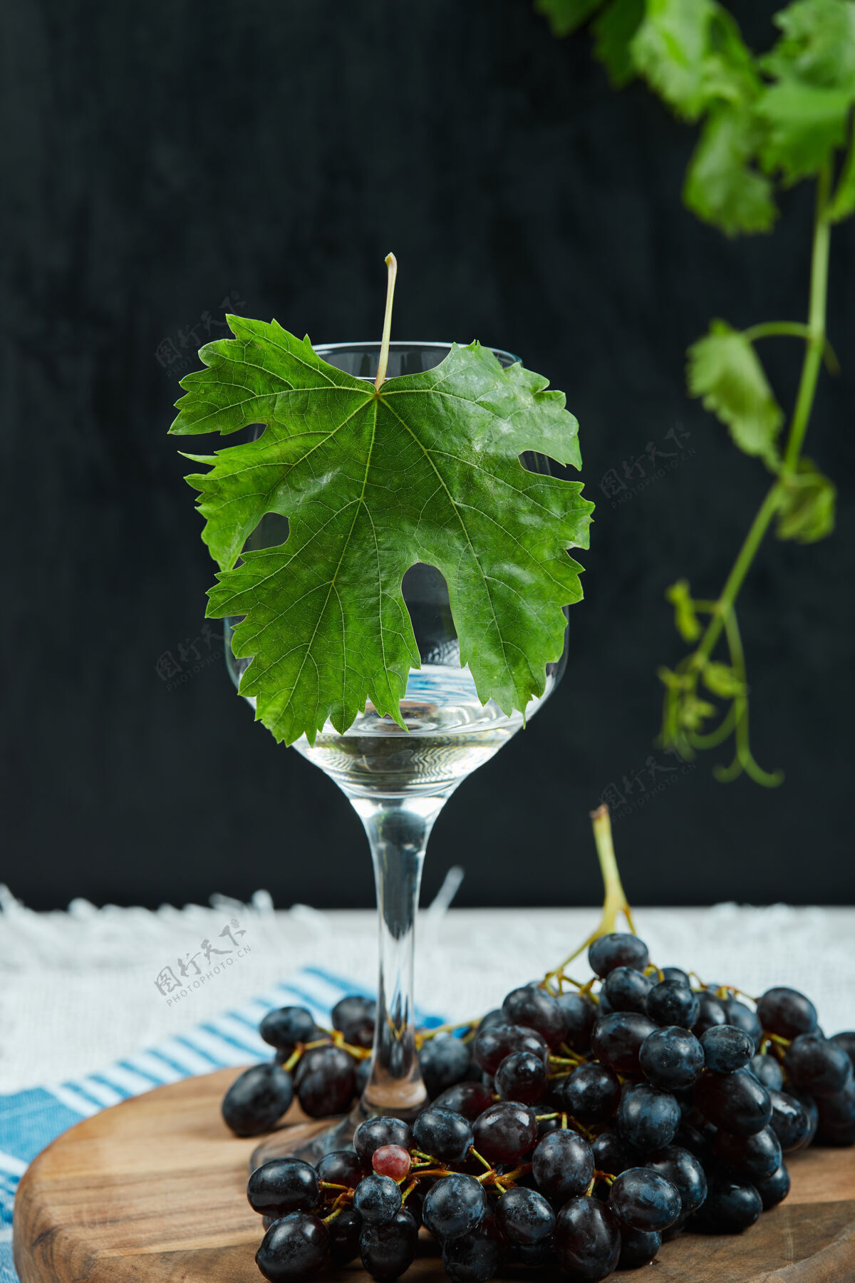 美味一盘黑葡萄和一杯深色背景上有叶子的葡萄酒高质量的照片大自然丛生桌布