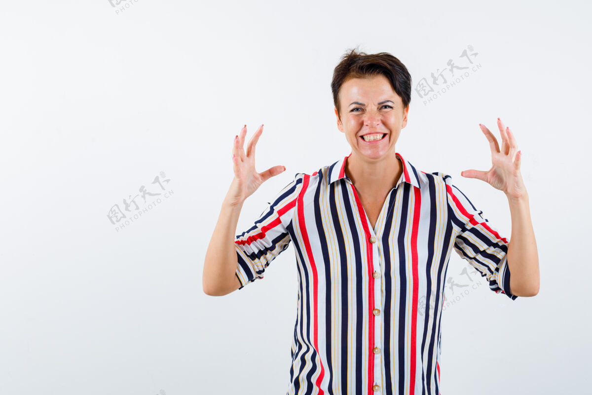 东西穿着条纹衬衫的成熟女人举起双手 紧握着什么东西 看上去很兴奋 正对着前方看健康老年人条纹