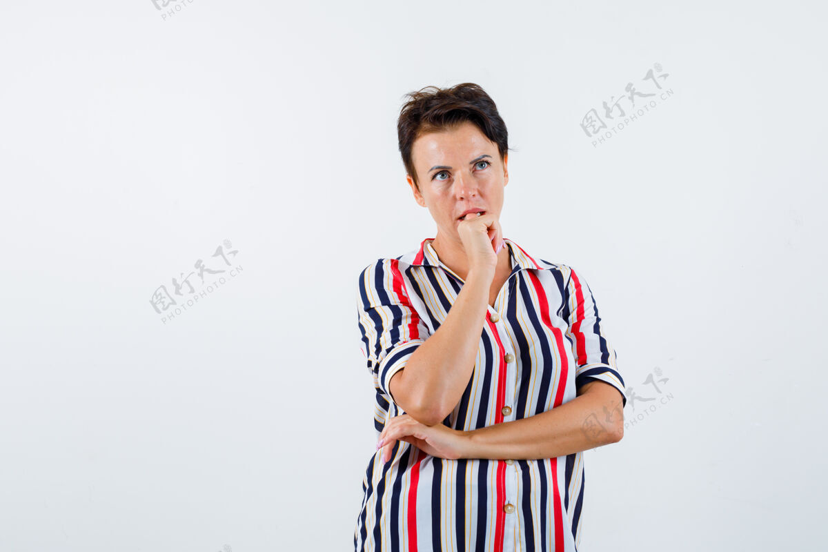 年龄成熟的女人把下巴靠在手掌上 想着条纹衬衫上的东西 神情沉思 俯视前方人瘦下巴