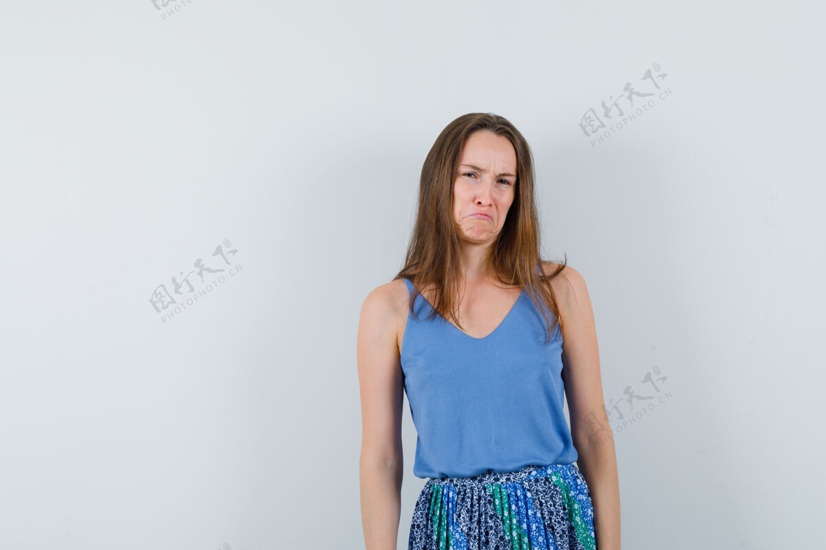 裙子年轻的女士看着相机在单身 裙子和看起来生气 前视图人单身女孩