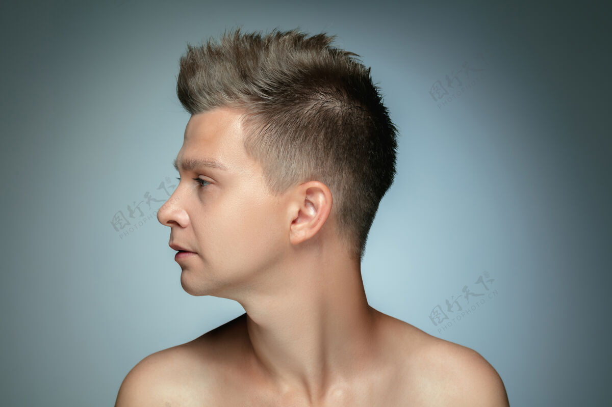 新鲜隔离在灰色墙上的赤膊青年的侧面肖像人时尚头发