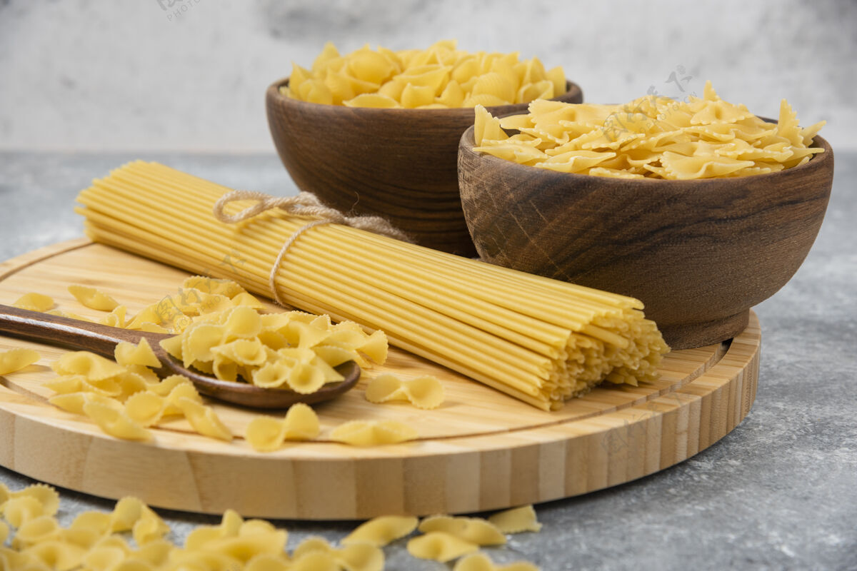 意大利面一碗碗生的干意大利面和放在大理石表面的意大利面碗营养烹饪