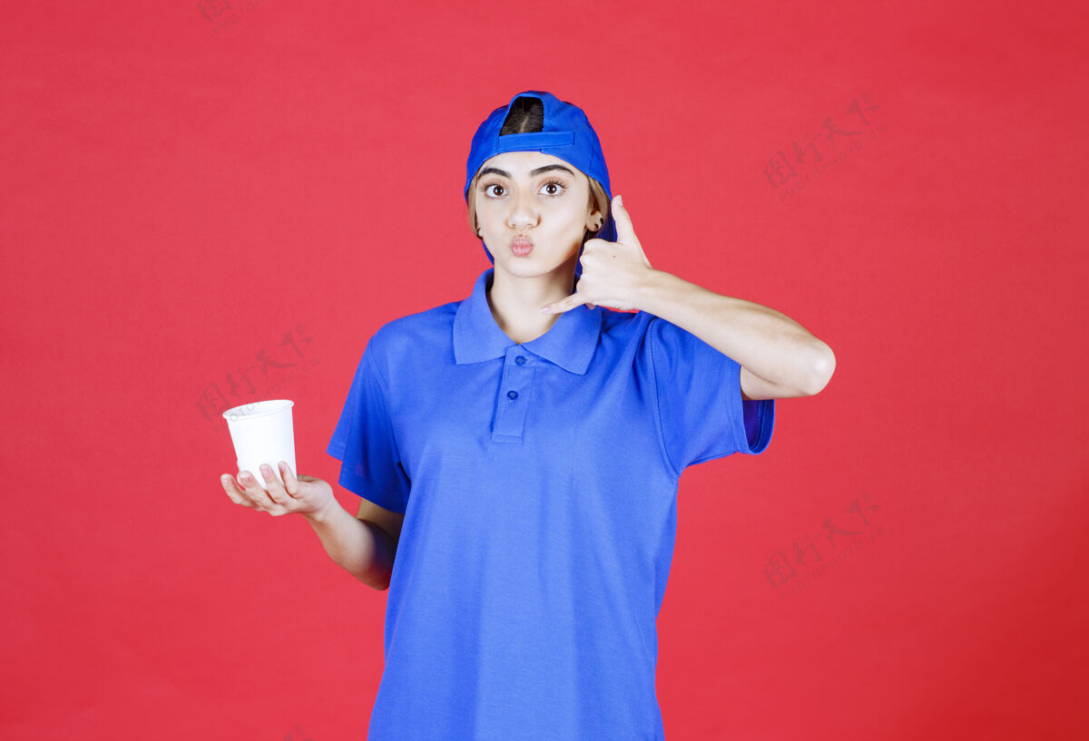 人穿着蓝色制服的女服务人员拿着一杯一次性饮料 要求打电话模特聪明人促销