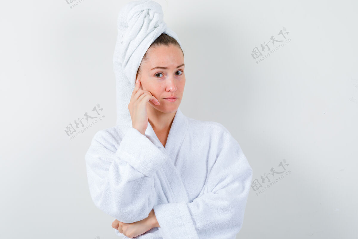 模特穿着白色浴衣 毛巾 手贴在脸颊上的年轻女孩 神情沉思 俯视前方微笑前面肖像