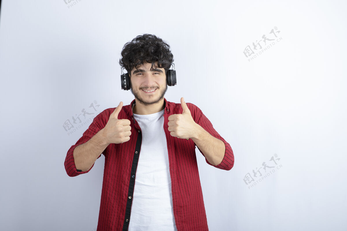 男人帅哥戴着耳机在白墙上听歌的画面年轻帅气耳机