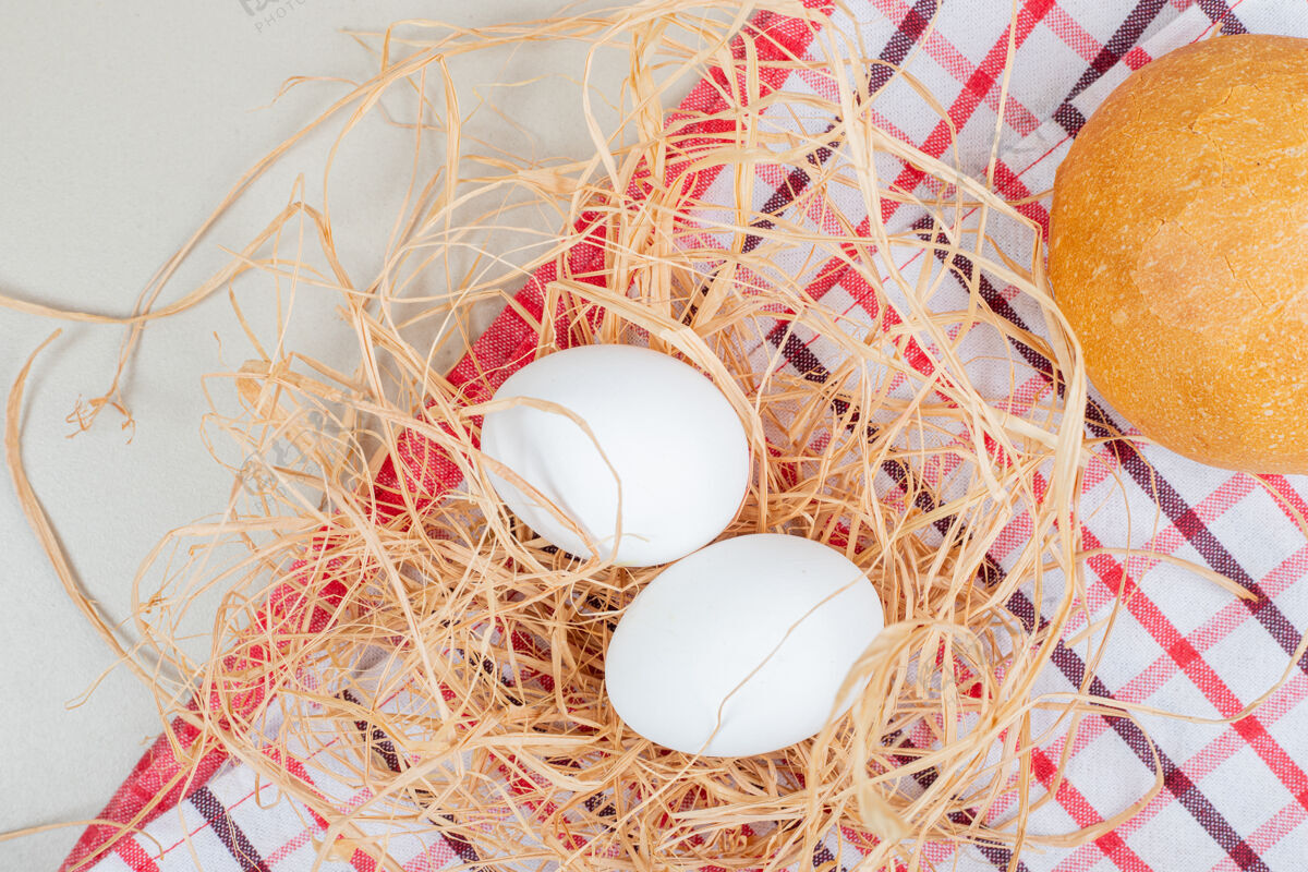 蛋壳两个煮熟的有机鸡蛋和桌布上的新鲜面包面包新鲜禽类