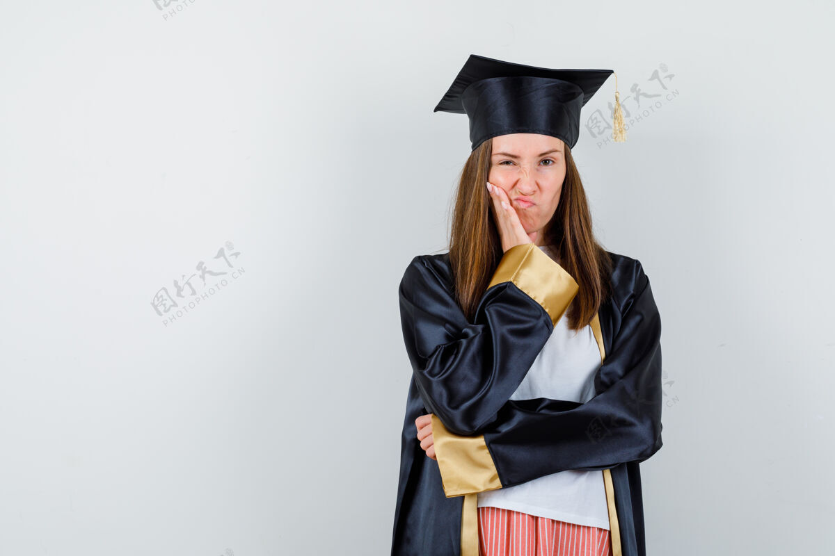 女孩女毕业生面颊靠在手掌上 嘴唇弯曲 穿着制服 穿着休闲服 看上去很不满意肖像多样性瘦削