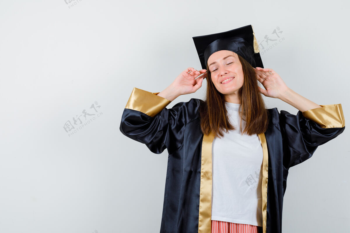 学院女毕业生的肖像摆姿势 而站在学院服装 并期待轻松的前视图成就学位Campus