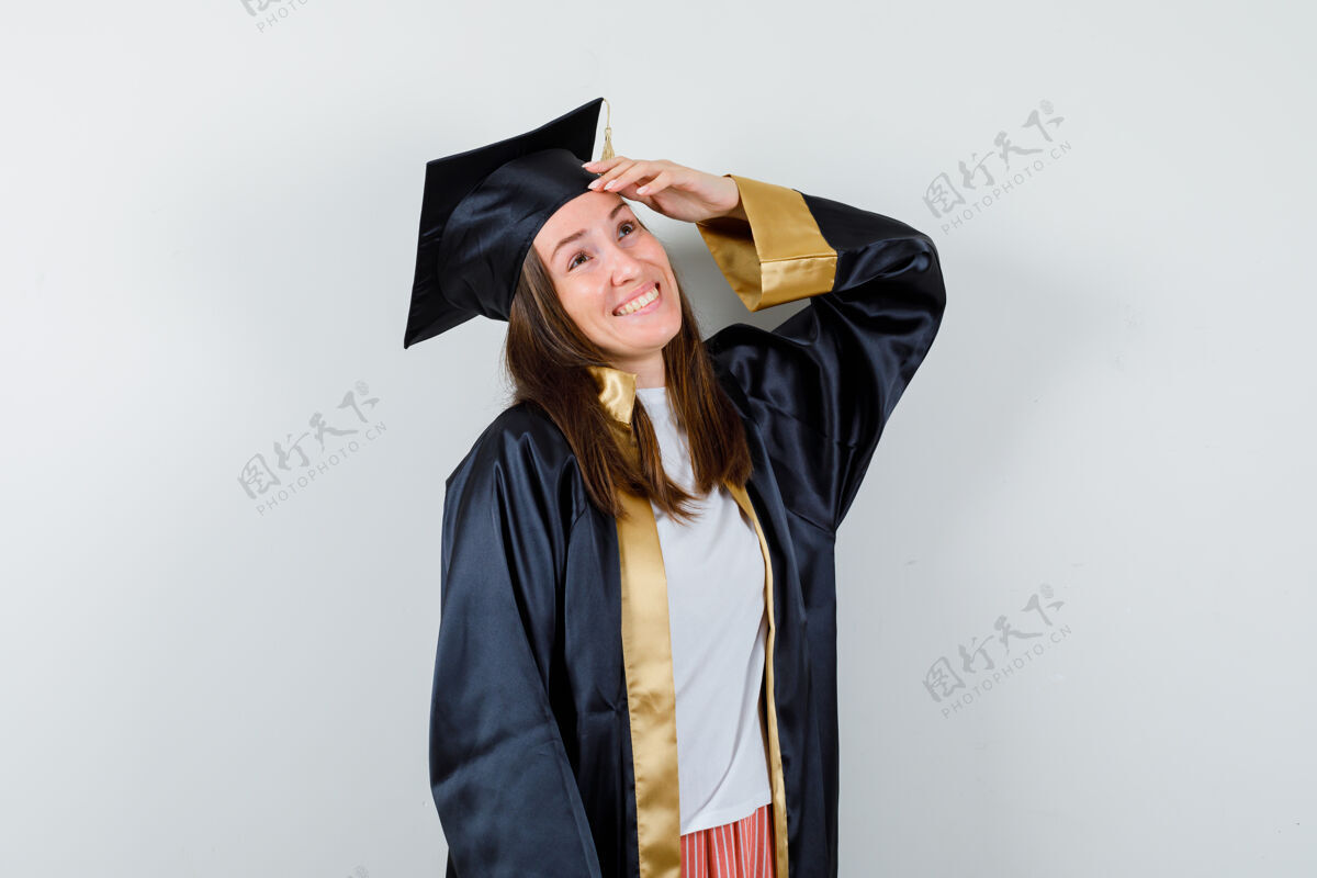 成功身着学院服的女毕业生手挽着手 看着幸福的前景色妇女长袍帽