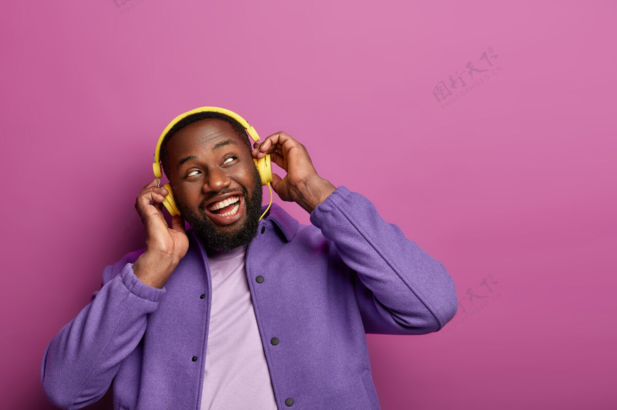耳机正面人物横观耳朵戴立体声耳机 欣赏现场音乐 侧目 是音乐女傧相 穿着随意 有爱好非洲耳机快乐