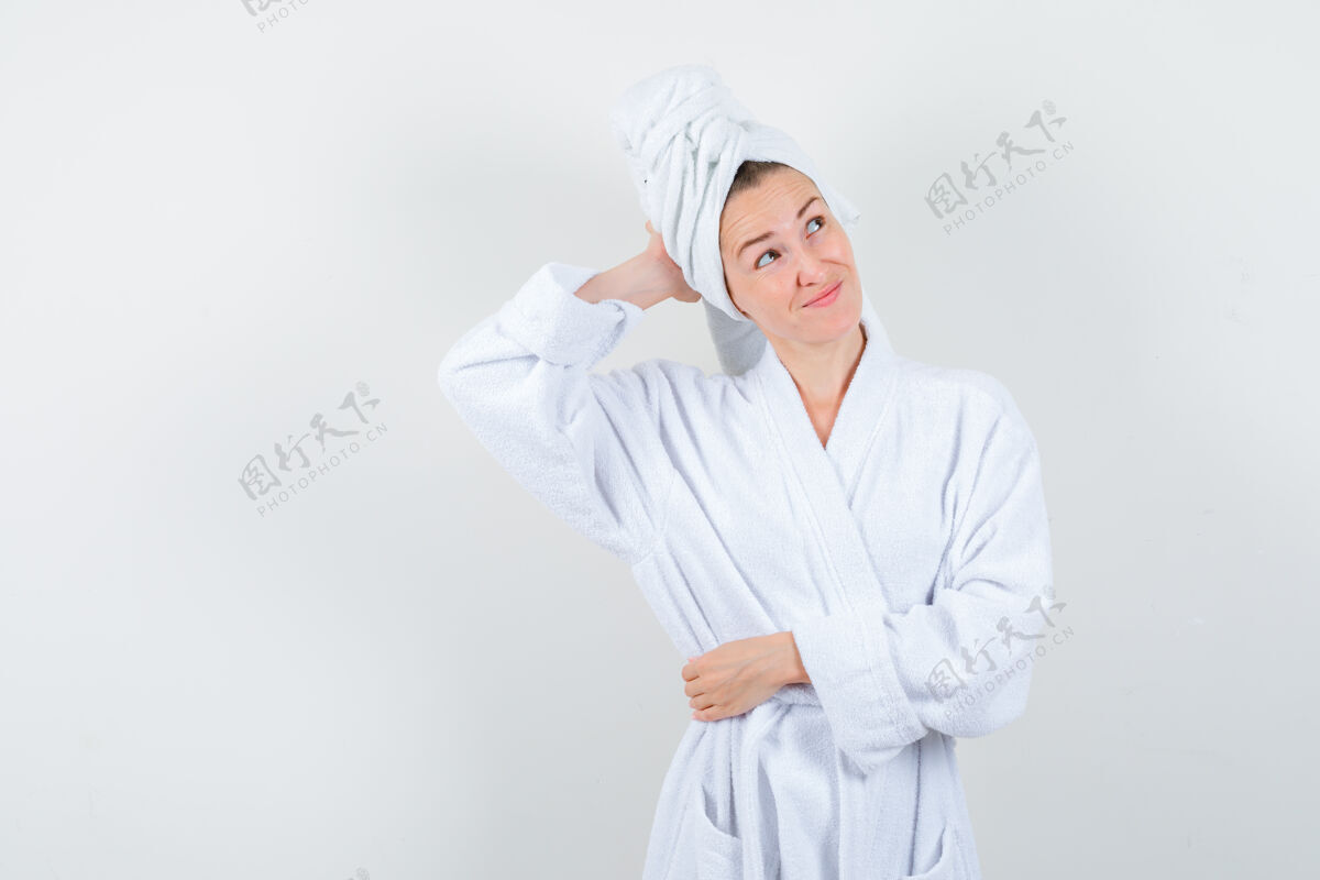 女士年轻女子手放在头后 穿着白色浴衣 毛巾 看起来健忘前视图皮肤时尚女孩