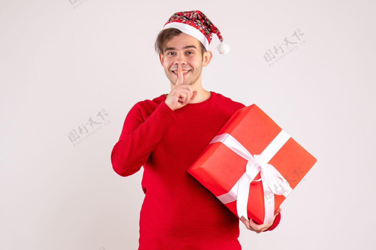 背景前视图：戴着圣诞帽的年轻人在白色背景上做嘘标志帽子快乐礼物