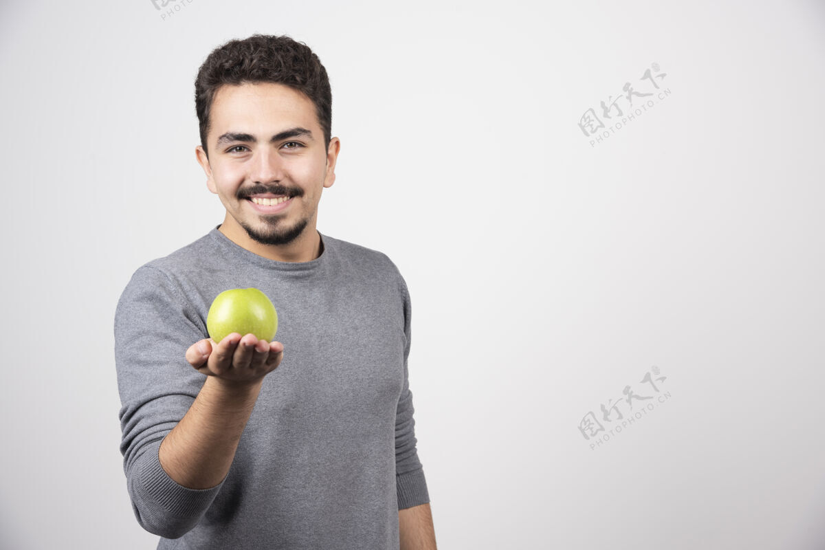 男性黑发男人高高兴兴地捧着青苹果苹果成人食物