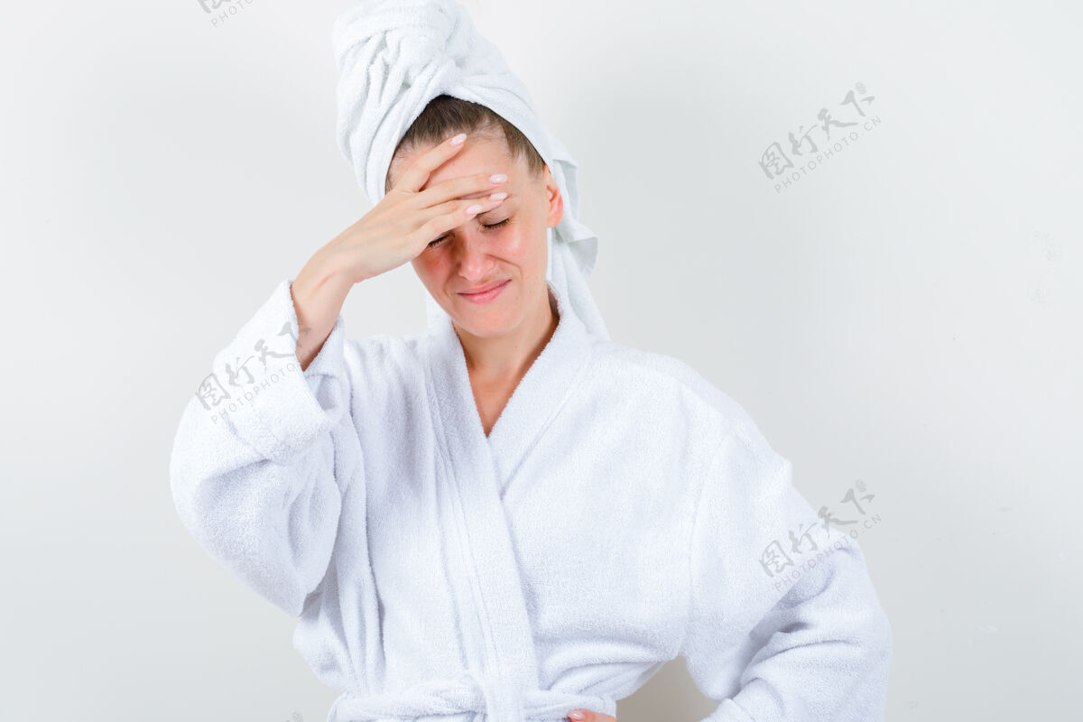 肖像穿着白色浴衣 毛巾的年轻女孩手捂着头 看上去很悲伤正面图模特成人女士
