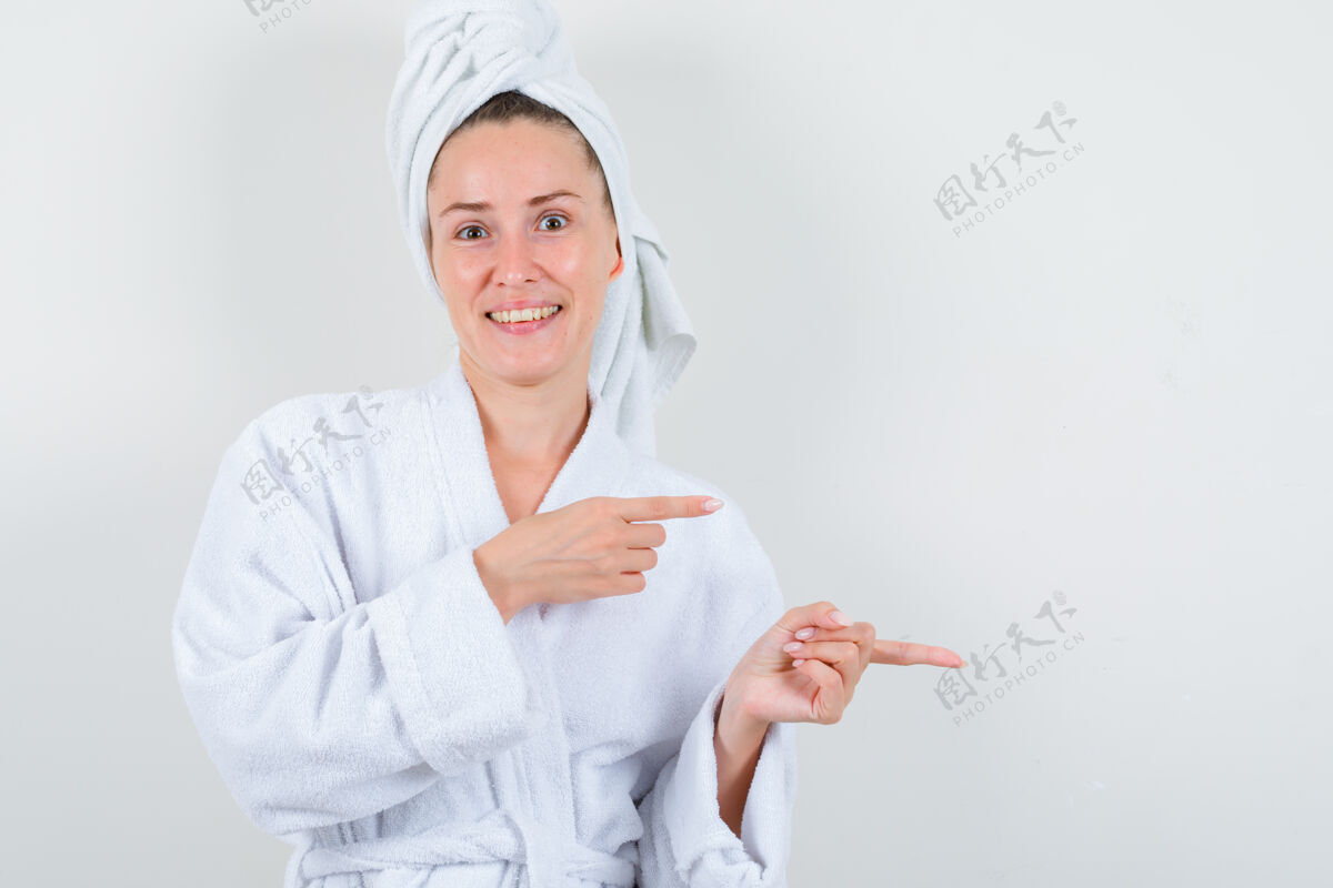健康穿着白色浴袍的年轻女士 毛巾指向一边 看上去很欢快 正前方的景色浴袍年轻亚洲人