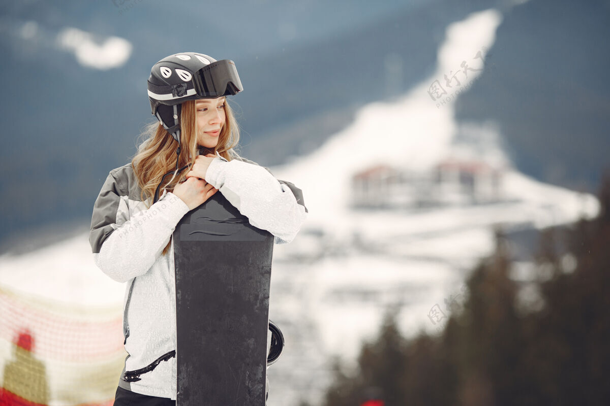 一个穿着滑雪板套装的女人在山上手拿滑雪板的运动员在地平线上关于运动的概念休闲下雪白