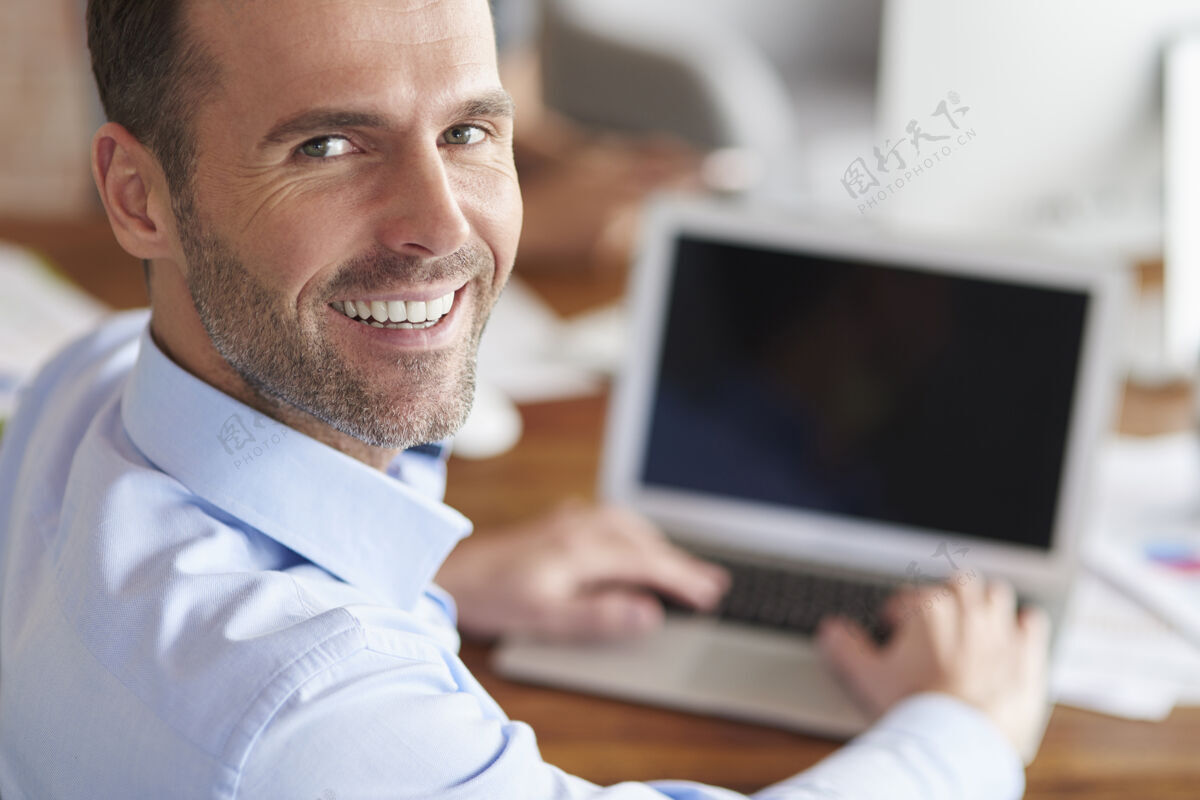 使用电脑开朗的男人在电脑上工作时 一边转身 一边微笑商人男人肖像