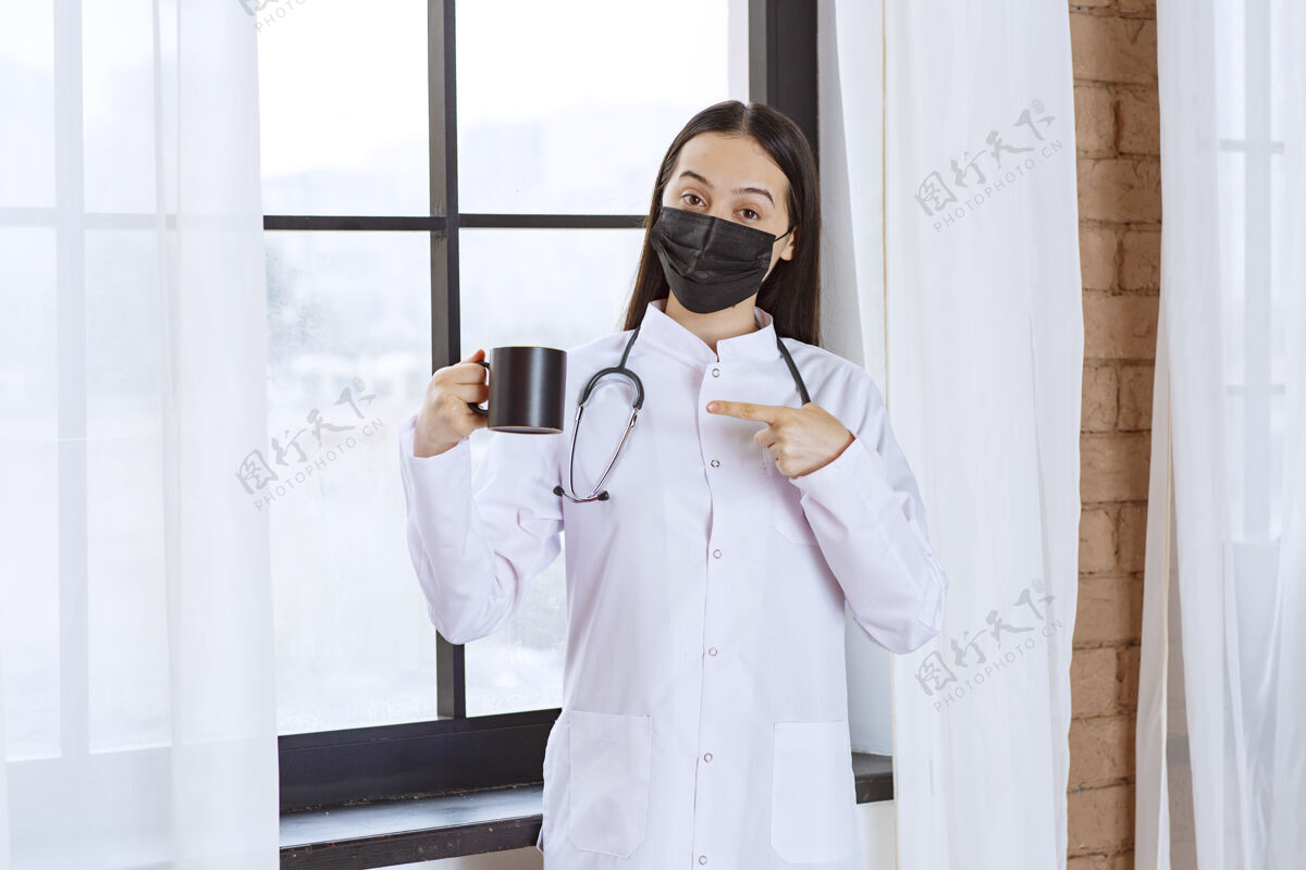 医学医生带着听诊器和黑色口罩 在休息时拿着一杯黑色的饮料制服疾病消毒