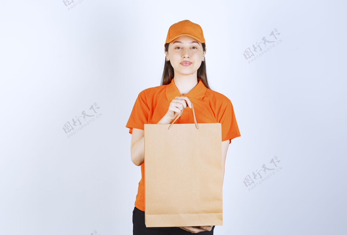 制服身着橙色制服的女服务人员拿着一个纸板购物袋 向顾客展示发货邮件员工