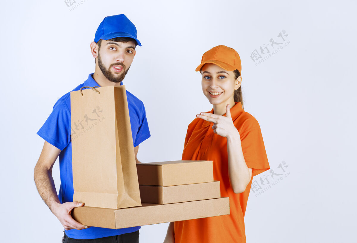 货物穿着蓝黄制服的男女快递员手里拿着纸板外卖盒和购物包男性人送货