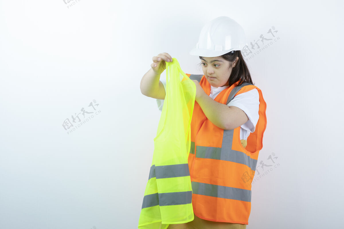 女人戴着安全帽的年轻女建筑工人 穿着白墙背心姿势残疾唐氏综合症