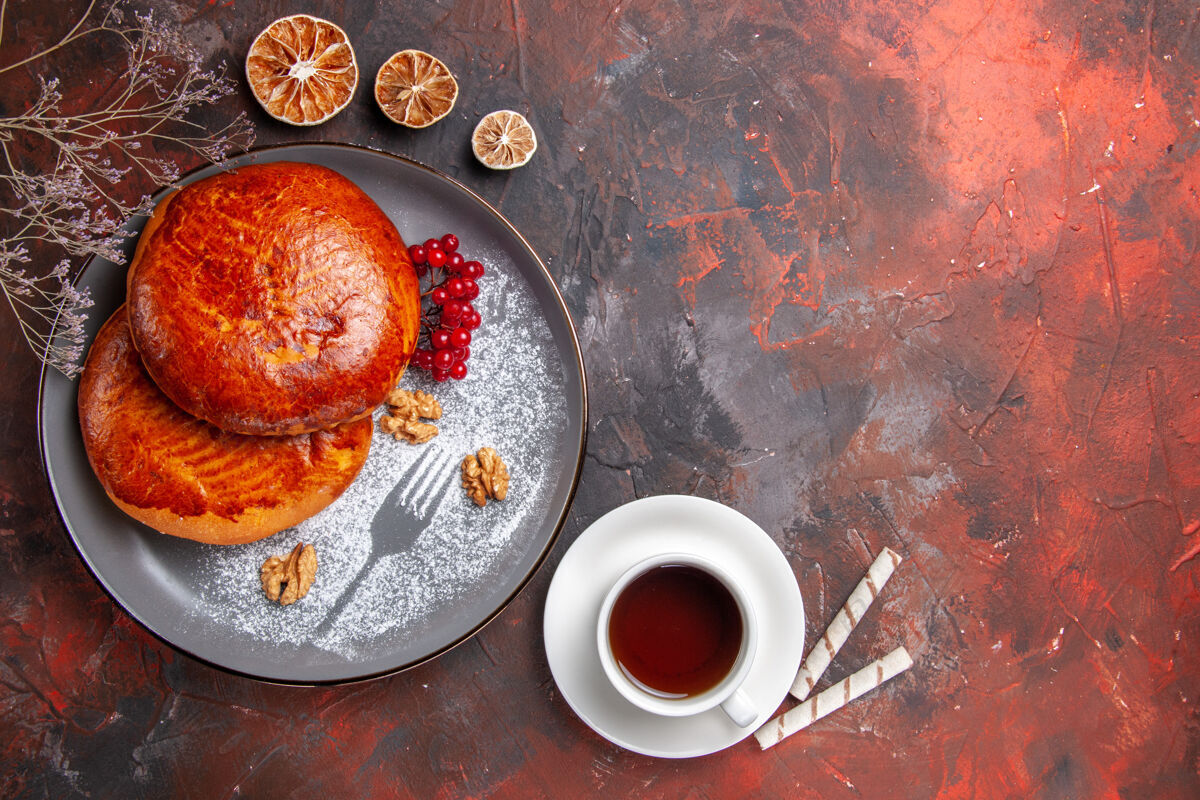 面包俯瞰美味的馅饼和一杯茶在黑暗的桌子上甜甜的馅饼蛋糕糕点咖啡茶托面包